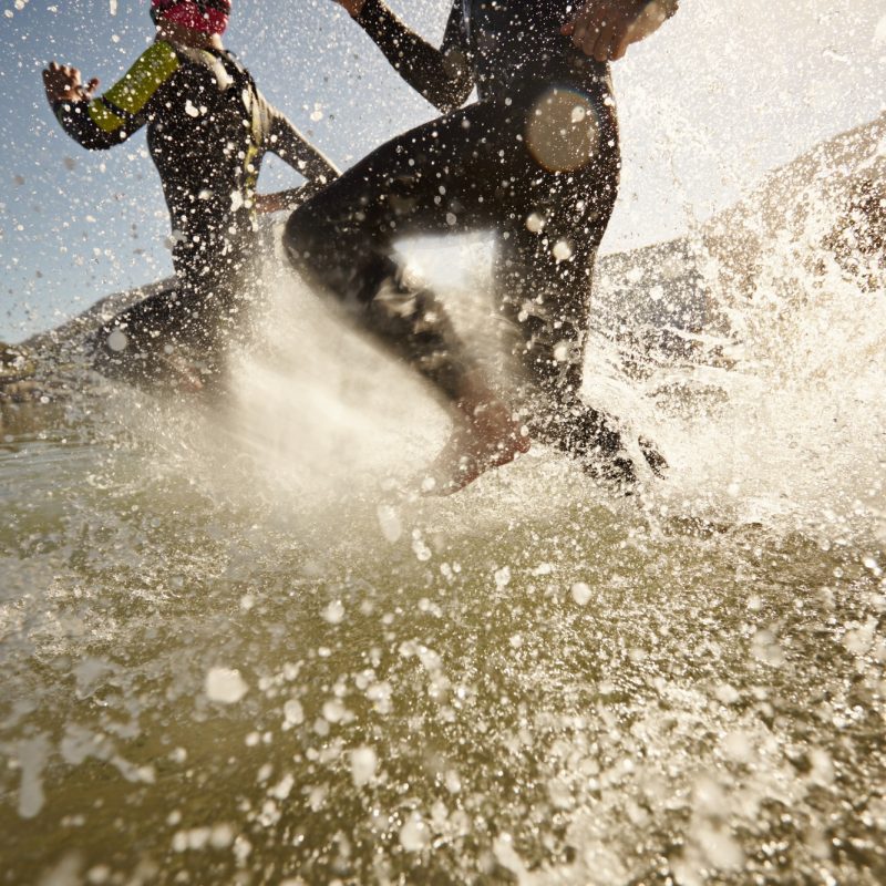 Triathlon participants running into the water for swim portion