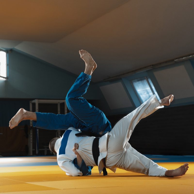 Two young judo fighters in kimono training martial arts in the gym with expression, in action and